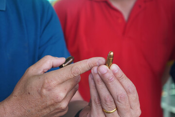 A shooting instructor is pointing at a 9mm pistol bullet in his hand.