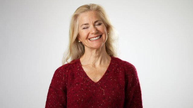 Portrait of happy smiling beautiful 50s middle aged mature woman looking at camera, laughing on white background. Anti age face beauty, skin and body care, wellness and self care concept