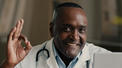 Naklejka premium Portrait african american ethnic elderly man mature doctor practitioner specialist therapist cardiologist dermatologist medical worker male specialist show ok gesture recommend good healthcare service