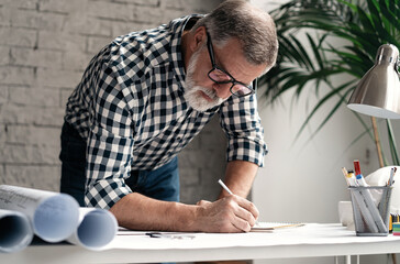 Mature Architect Engineer Design Working Planning Concept. Portrait of businessman working on blueprints at the office