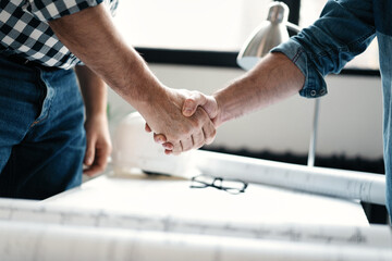 Fototapeta na wymiar Architect and engineer workers shaking hands while working for teamwork and cooperation concept after finish a deal