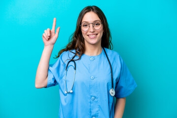 Young surgeon doctor woman isolated on blue background pointing up a great idea
