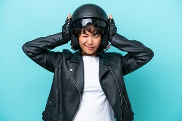 Young Argentinian woman with a motorcycle helmet isolated on blue background frustrated and covering ears
