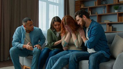 Obraz premium Sad desperate girl talk share problem with friends in group psychological therapy at home diverse ethnic women men help upset girl. Caring multiracial teammates listen complaints support give advice