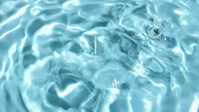 Video of water splashes and falling drops on a blue background. Water drop splash blue colored.