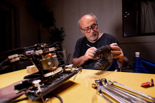 man concentrating on cleaning a tool on his workbench