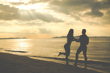 Fototapeta premium silhouette couple in love on summer beach sunset. Happy romantic couple enjoying and relaxing on the Beach