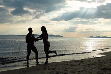 Fototapeta premium silhouette couple in love on summer beach sunset. Happy romantic couple enjoying and relaxing on the Beach