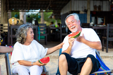 Elderly couple. smiling senior couple eating watermelon on the beach having fun
