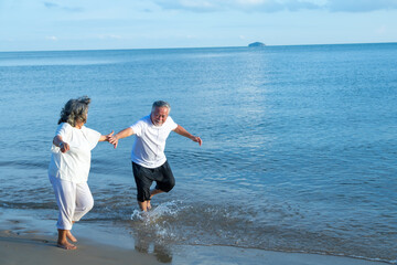 Elderly couple. Joyful nice elderly couple smiling and happy running on the beach