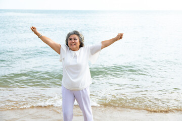 happy elderly woman doing exercise on beach.