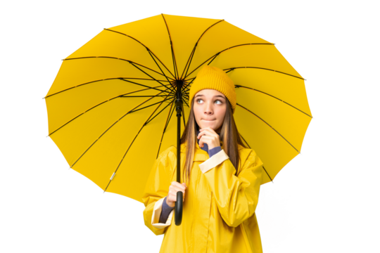 Teenager girl with rainproof coat and umbrella over isolated chroma key background having doubts and thinking