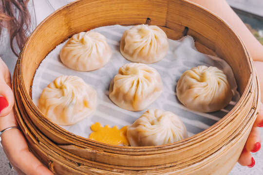 A delicious, traditional Chinese delicacy, Xiao Long Bao dumplings, presented in a bamboo plate for an authentic touch.