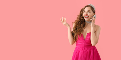 Beautiful young woman in stylish prom dress talking by phone on pink background with space for text