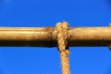 Tied neatly with twine of brown hemp rope to several large pieces of bamboo. The background is a bright blue sky.