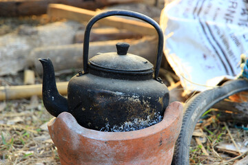 black old kettle been used for a long time on a small brown furnace.