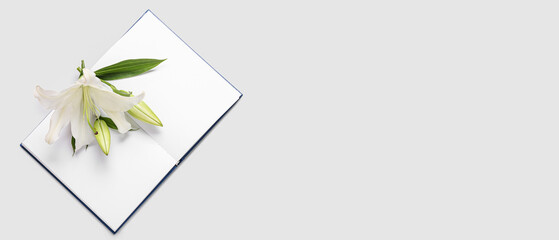 Beautiful lily flowers and blank book on light background with space for text
