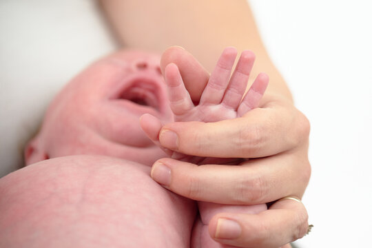 HOUSTON, TEXAS - APRIL 26TH 2023: a newborn baby’s tiny pink fingers are photographed close up in their mother’s hands to compare the size. You can see every detail and line on the skin.