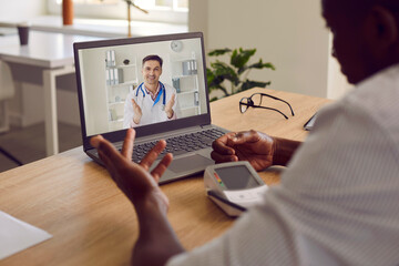 Man with hypertension using digital sphygmomanometer device for arterial pressure self examination test asks online doctor treatment advice during telemedicine videocall on laptop notebook PC computer