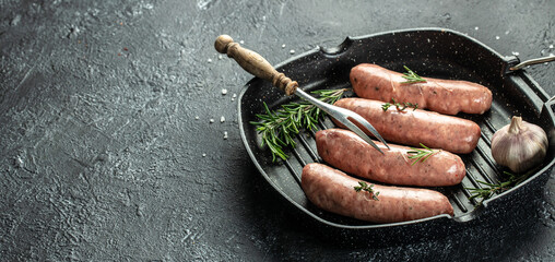 Raw sausages and ingredients on the grill pan ready to cook. Grilling food, bbq, barbecue. Long...