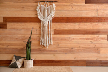 Pot with big cactus and stylish macrame near wooden wall