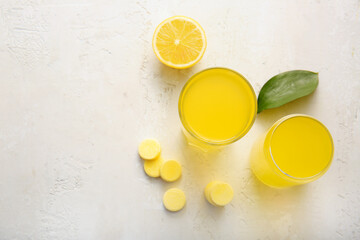 Glasses of vitamin C effervescent tablet dissolved in water and lemon on white grunge table