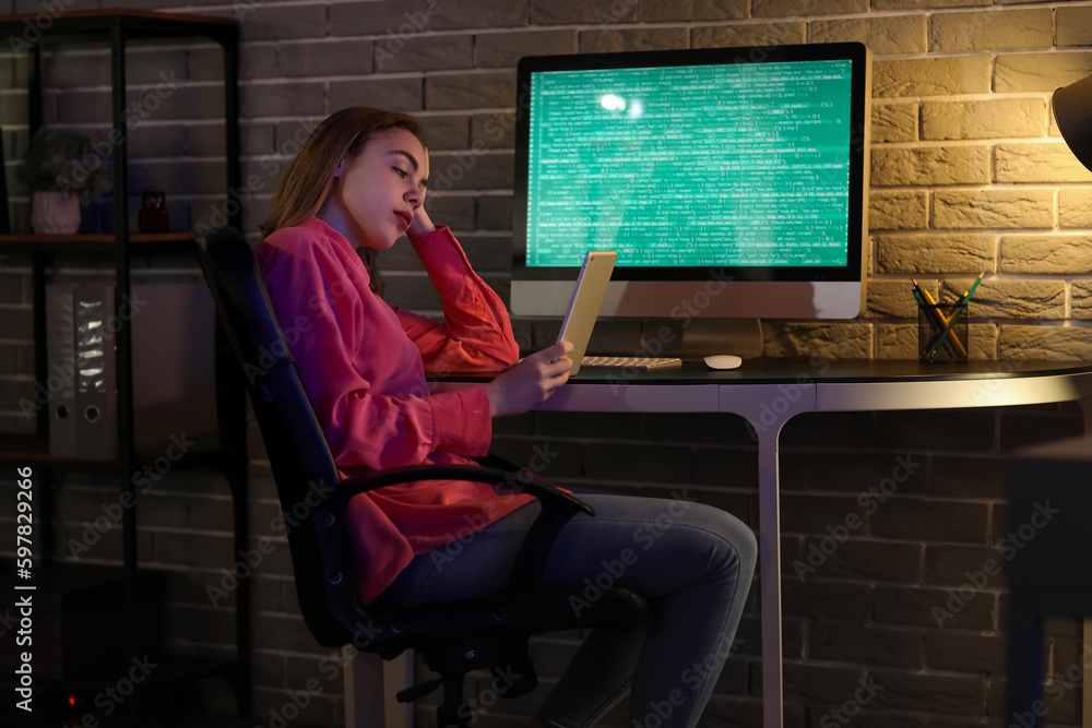 Poster female programmer working with tablet computer in office at night