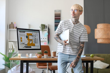 Tattooed graphic designer with laptop in office