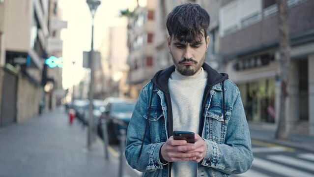 Young hispanic man using smartphone at street