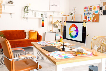 Graphic designer's workplace with computer, tablet and color palettes in office