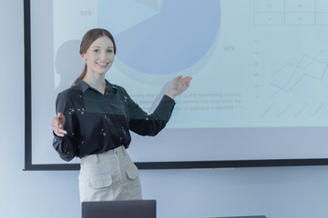 Woman standing at the front projector presenting her idea to colleagues in meeting room . Businesswoman public speaking in a conference meeting.