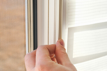 The man wipes the window frame with a degreaser and glues a sealing rubber tape on it for noise...