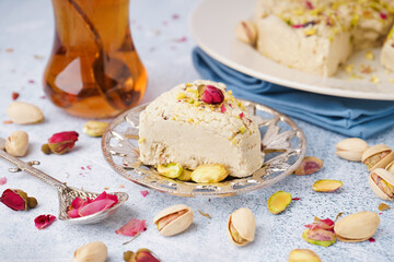 Plates of tasty Tahini halva with pistachios on light background