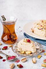 Plates with tasty Tahini halva and glass of Turkish tea on light background