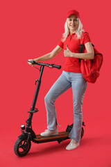 Mature courier with electric bike showing thumb-up on red background