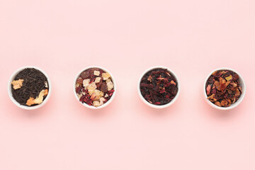 Bowls with different dried fruit tea on pink background