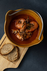 A bowl of soup with two pieces of bread on a wooden board.