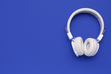 Modern white headphones on blue background