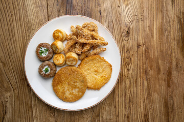 A plate of fried meats with a fried chicken and fried potato.