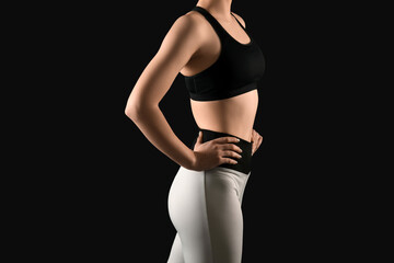 Fototapeta premium Sporty young woman in leggings on black background