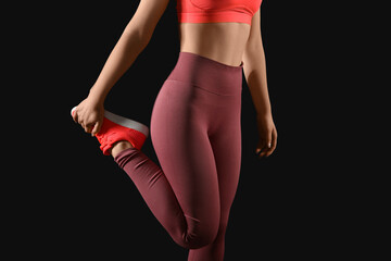 Sporty young woman in leggings on black background - obrazy, fototapety, plakaty
