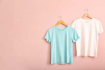 White and blue t-shirts hanging on pink wall