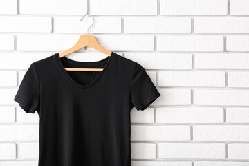 Black t-shirt hanging on white brick wall