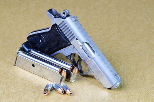 The compact Semi automatic pistol, stainless steel PPKs pistol with spare magazines right side view, Ready for use, lying isolated on white background.