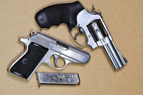 The compact revolver gun, stainless steel j-frame m60 pistol and compact Semi automatic pistol PPKs isolated on brown background.
