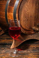 Oak barrel with glass of wine on wooden background