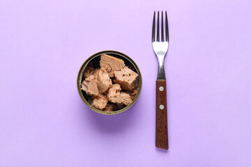 Opened tin can with delicious tuna and fork on lilac background