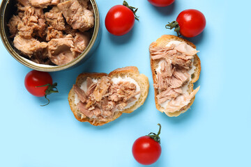 Delicious tuna bruschettas, tin can and tomatoes on blue background
