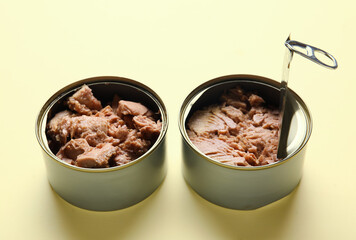 Opened tin cans with delicious tuna on beige background