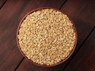 Dry oat flakes in a clay bowl on a wooden background. Dry rolled oatmeal on wooden boards. Healthy eating concept. Copy space. Top view